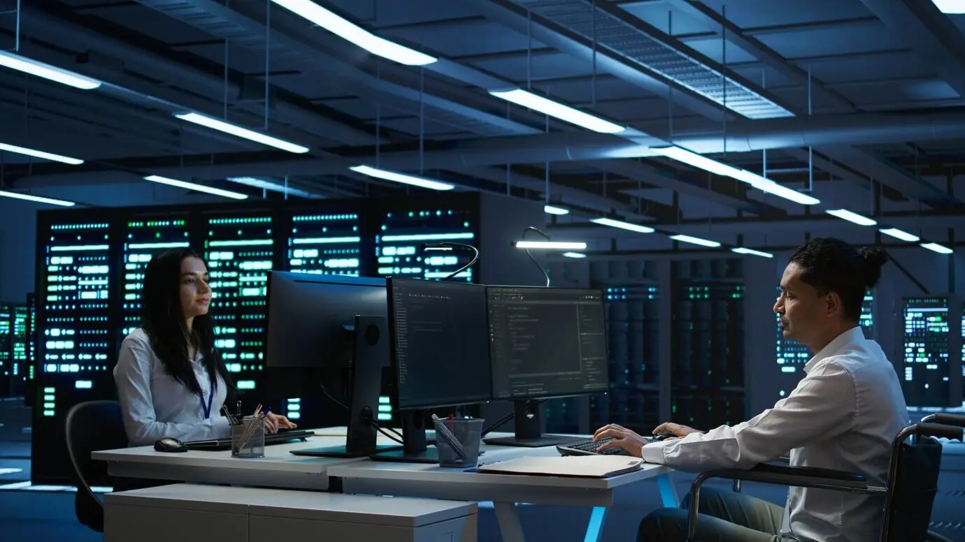 Mujer en silla de ruedas realizando mantenimiento en la infraestructura de la sala de servidores.