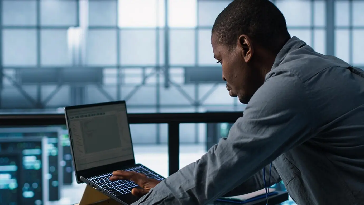Técnico en un centro de datos usando lenguajes de programación en una computadora portátil.