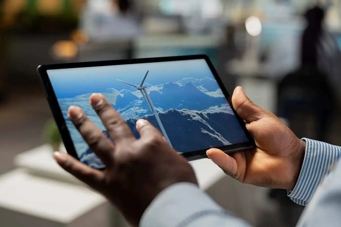 Primer plano de un ingeniero en una oficina usando una tableta para analizar una turbina eólica.