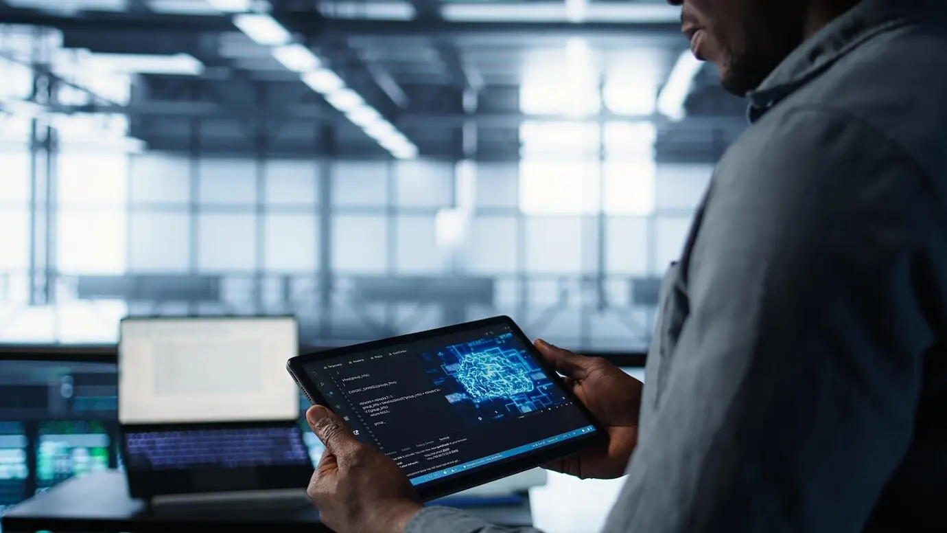 Primer plano de un científico de la computación en un centro de datos que utiliza IA en una tableta.